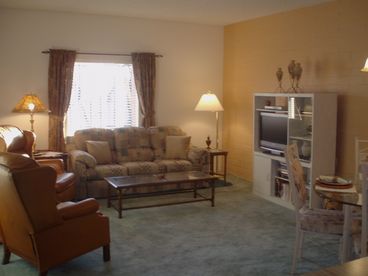 Living room with sofa, two all leather full recliners, flat screen TV, DVD, open plan to dining and kitchen.