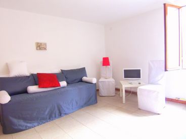 living room, with dining table in the center and two single beds that, during the day, are used like sofa.