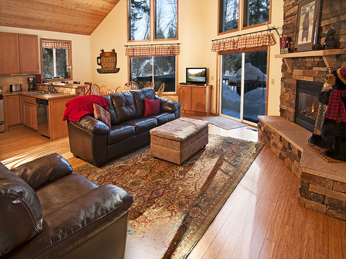 Modern and charming interior with rock fireplace, hardwood floors, and leather furniture. 