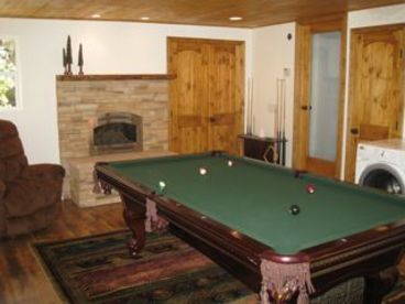 New game room addition with pool table, second fireplace, washer and dryer, and views of surrounding oaks and pine trees.