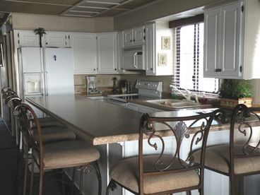 Full kitchen has a range, refrigerator, dishwasher and breakfast bar with 5 stools