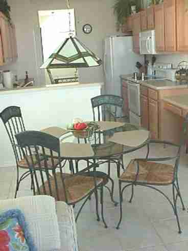 Breakfast room, kitchen and dining room in the distance.  Picture taken from the family room which opens to screened lanai. Corian countertops, upgraded appliances (double door frig with icemaker, microwave, quiet dishwasher,ceramic top stove,self cleaning oven, double white porcelain sinks, disposal, solid maple cabinetry, two ceiling fans, ceramic tile floor.  Extensive kitchen gadgets/equipment/supplies, Large pantry. 