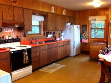 Kitchen has large dining table with windows facing Yellow Birch Lake