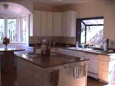 This spacious kitchen boasts granite counters, 2 ovens, gas range, pantry, nook, & all the utencils & small appliances you could think of. Also, to the right of photo is a sliding glass door which leads to the wrap around deck with barbeque and patio furniture.