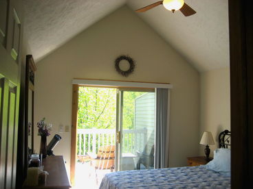 Master Bedroom with sliding glass door onto deck with 2 adironack chairs and table