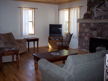 This spacious living room has wood floors, gas fireplace with unique driftwood mantel, and views of the flowage.