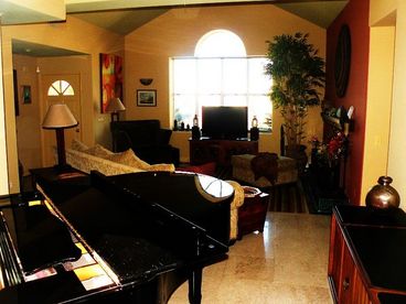 Baby grand piano in the music alcove with sliding glass door opens onto colonnade, pool and garden
