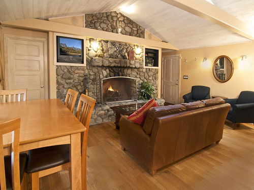 River rock fire place with leather furniture and additional seating, combined with dining table that looks out over the river.