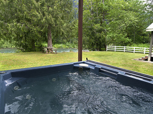 Covered hot tub situated between the main house and guest house, with river views.