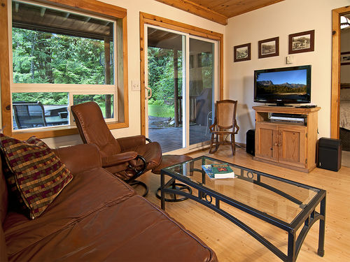 Spacious living room with hardwood floors, leather furniture a flat screen television, and nearby wood burning stove.