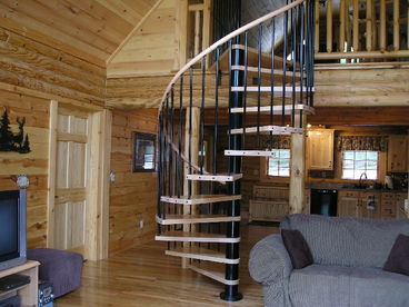 Circular stairs lead to the large loft area overlooking the Great Room and view outside