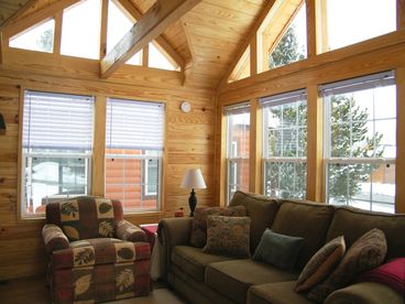 Living room with chalet dormers, ceiling fan, and sliding glass doors to the covered deck.  TV with DVD and stereo.  