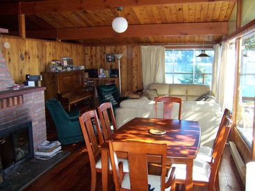 This is the front room with it\'s large windows facing the view of Long Harbour.  Note the wood finish and central fireplace.