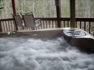 Large hot tub on lower deck overlooking waterfalls