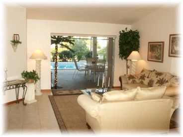 Spacious tropical living area opens to beautiful waterfront screened pool/lanai surrounded by palms. 