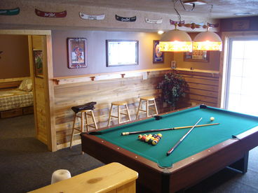 Pool table and lounge area with adjacent bedroom and sliding glass door leading to an impressive deck with lake access.