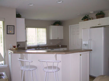 Kitchen is bright with breakfast bar and fridge with icemaker.
