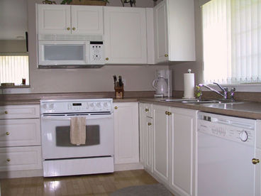 Kitchen has modern appliances. Dishwasher, stove with ceramic cooktop, microwave with hood fan.