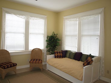 Air conditioned sunroom with a ceiling fan featuresthree walls of windows, comfortable seating and a daybed with a trundle