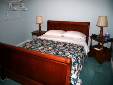 Queen sleigh bed with comforter, side tables and clothes hanging rack.  Crib, luggage racks, dresser off camera in the bedroom as well.