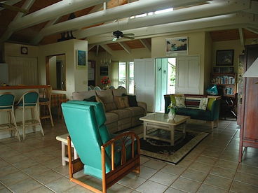 The upstairs Great Room is airy and spacious with cathedral ceilings and lots of windows. This connects to both front and back lanais, the front and back yards and the main kitchen and dining room.