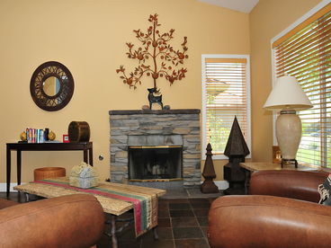 Living area with overstuffed leather furniture and wood burning stone fireplace.