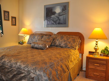 The master suite has an adjacent bath, and a view of the wooded land setting.