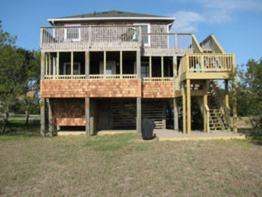 The back of the house has a screened porch and sun decks overlooking the Turtle Pond and Cape Hatteras National Park.