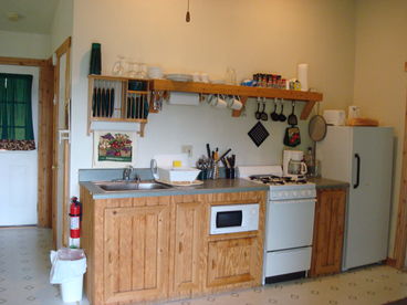 Kitchen with stove,oven,microwave, coffee pot, refrigerator, pots, pans, glasses, silverware, plates.