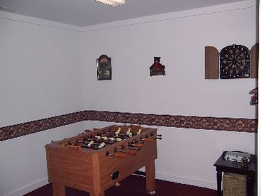 Game room with foosball table, dart board, games, and ping pong table.