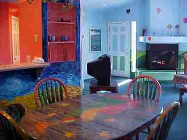 This is a view from the dining area with cathedral ceilings and unique wall art including hot air balloons and fluffy clouds floating amongst the light blue sky.