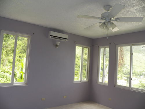 Bedroom with split airconditioner, fan and plenty of outside spilling in.  So new that curtains are not installed yet, but soon.