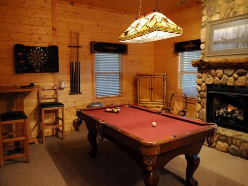 Game room with pool table, darts, TV, and fireplace.