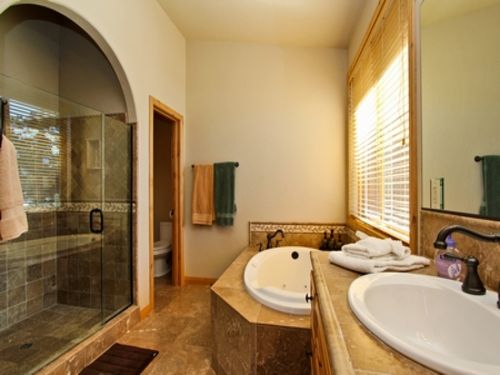 A large bathroom with a sunken bathtub, dual sinks with granite counter tops, a separate shower