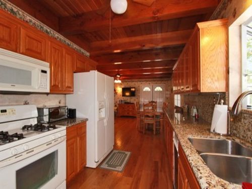 The living room opens up to the kitchen and dining area with beamed ceilings and wood floors