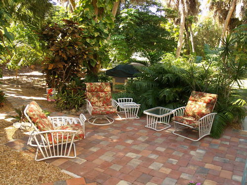 Furnished patio with barbecue and pathways through tropical garden.
