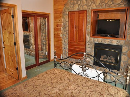 Master Suite with Queen Bed, Gas Fireplace, and TV. Bathroom has a Jetted Bath Tub and separate Shower Stall, plus vanity with dual sinks. 