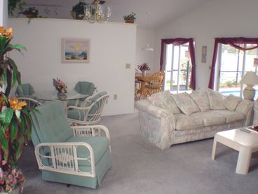 View of open plan living area showing dining area, living area and breakfast nook under vaulted ceilings.