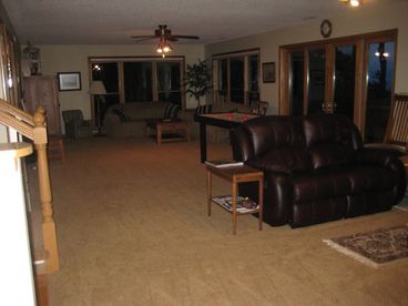 sitting area by wood buring fireplace in center of great room, TV area at far end of great room