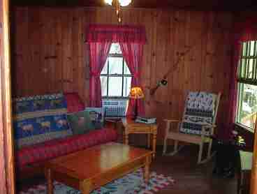 UNWIND IN THE RUSTIC SURROUNDINGS OF THE KNOTTY PINE LIVING ROOM WITH RED PLAID CURTAINS AND QUEEN FUTON