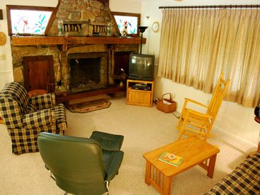 Living room with charming rock fireplace surrounded by hummingbird stained glass