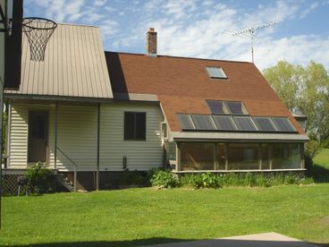 View from garage area of side of house. Sun room has hot tub and full skylight windows above for view of stars and northern lights.