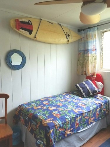 Twin Bedroom with Surfboard on the wall.
Has 2nd bed and 5 Drawer Dresser & Sliding Mirror closet plus chair,  large ceiling fan and portable fan.