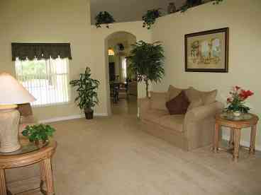 The tastefully furnished living room offers guests the opportunity for quiet relaxation in soft comfortable chairs. A large picture window overlooks the pool area. 
