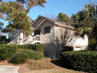 Front of home with large yard and lush landscape.