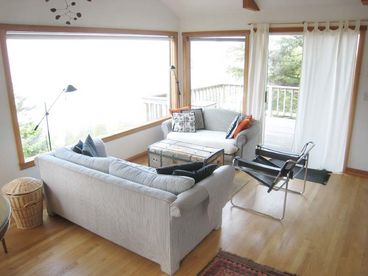 The large picture window overlooks the ocean and cliff. The sliding door at right opens onto the large deck.