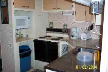 Small working kitchen well stocked with cooking and baking dishes as well as toaster, microwave, coffeemaker and watercooler.